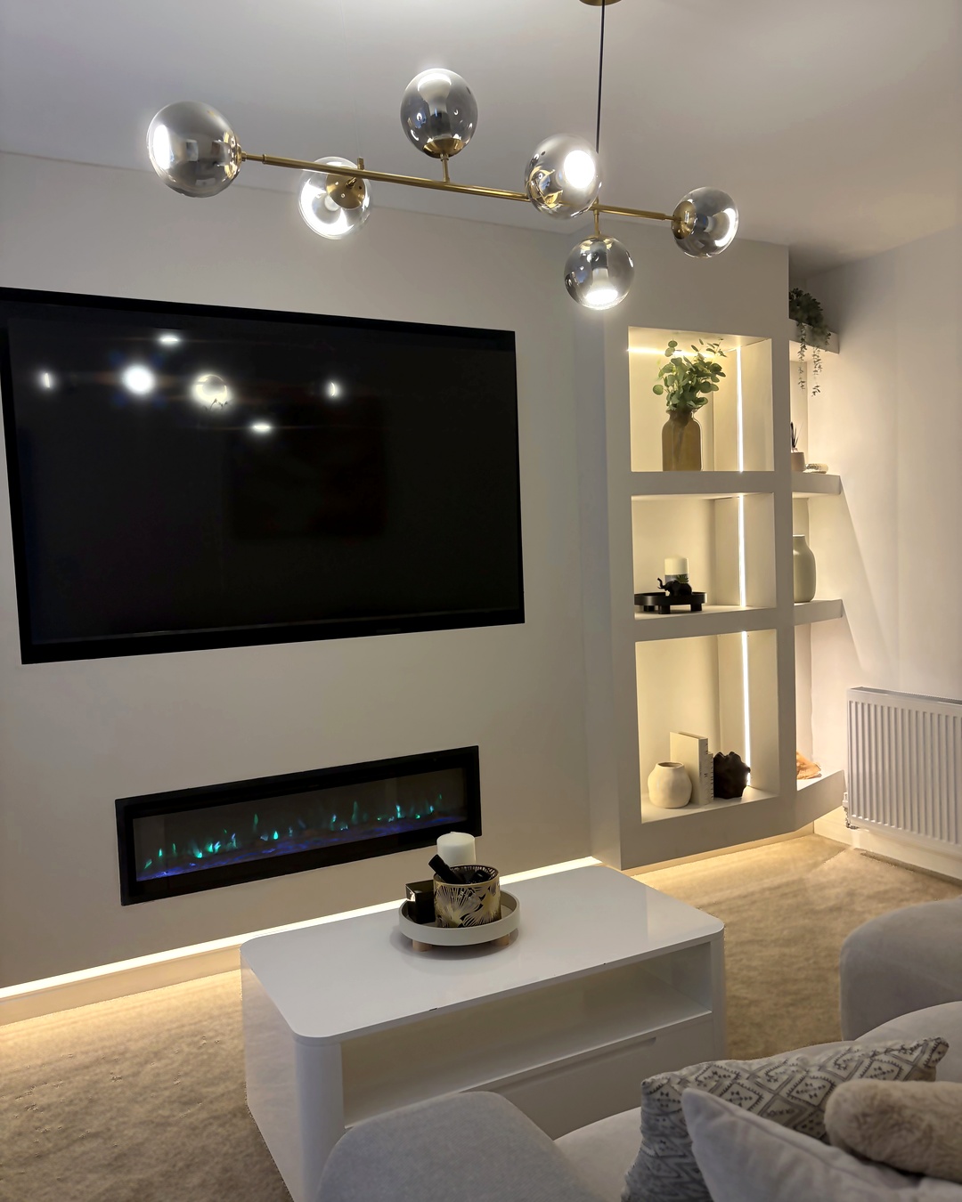 Bespoke media wall with a recessed television, electric fire and lit display niches